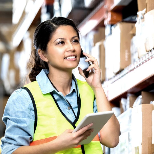 woman talking through a phone in a logistics environment