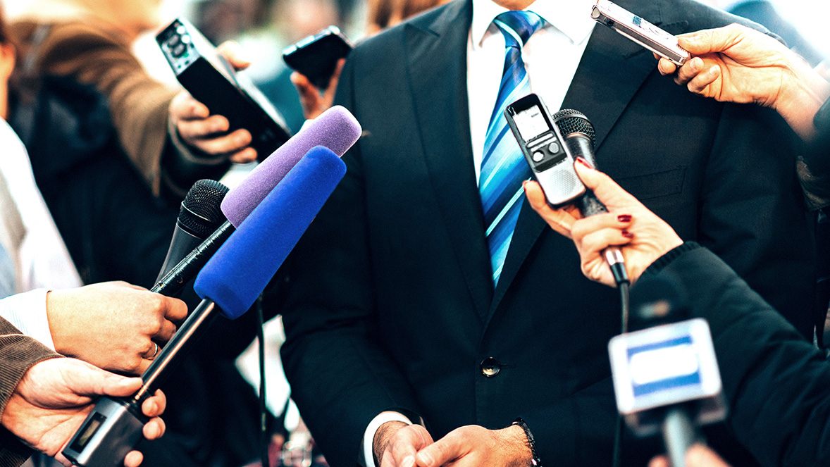 close up of businessman surrounded by microphones