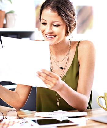 woman smiling while reading a document